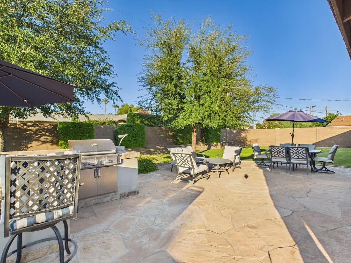Stunning backyard retreat featuring a private pool with a waterfall, sun loungers, BBQ grill, outdoor seating, Smart TV, and an outdoor dining area.