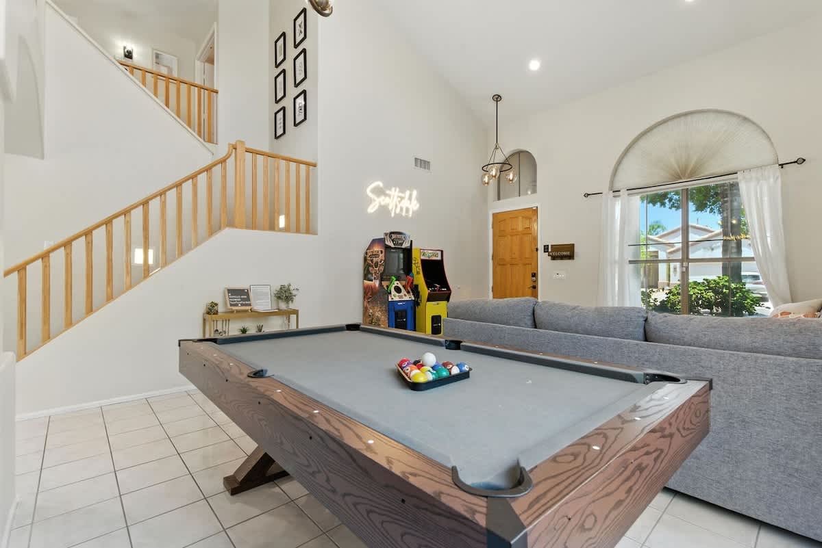 Second living area/game room with arcade games, coffee table, and pool table. (1st Floor)