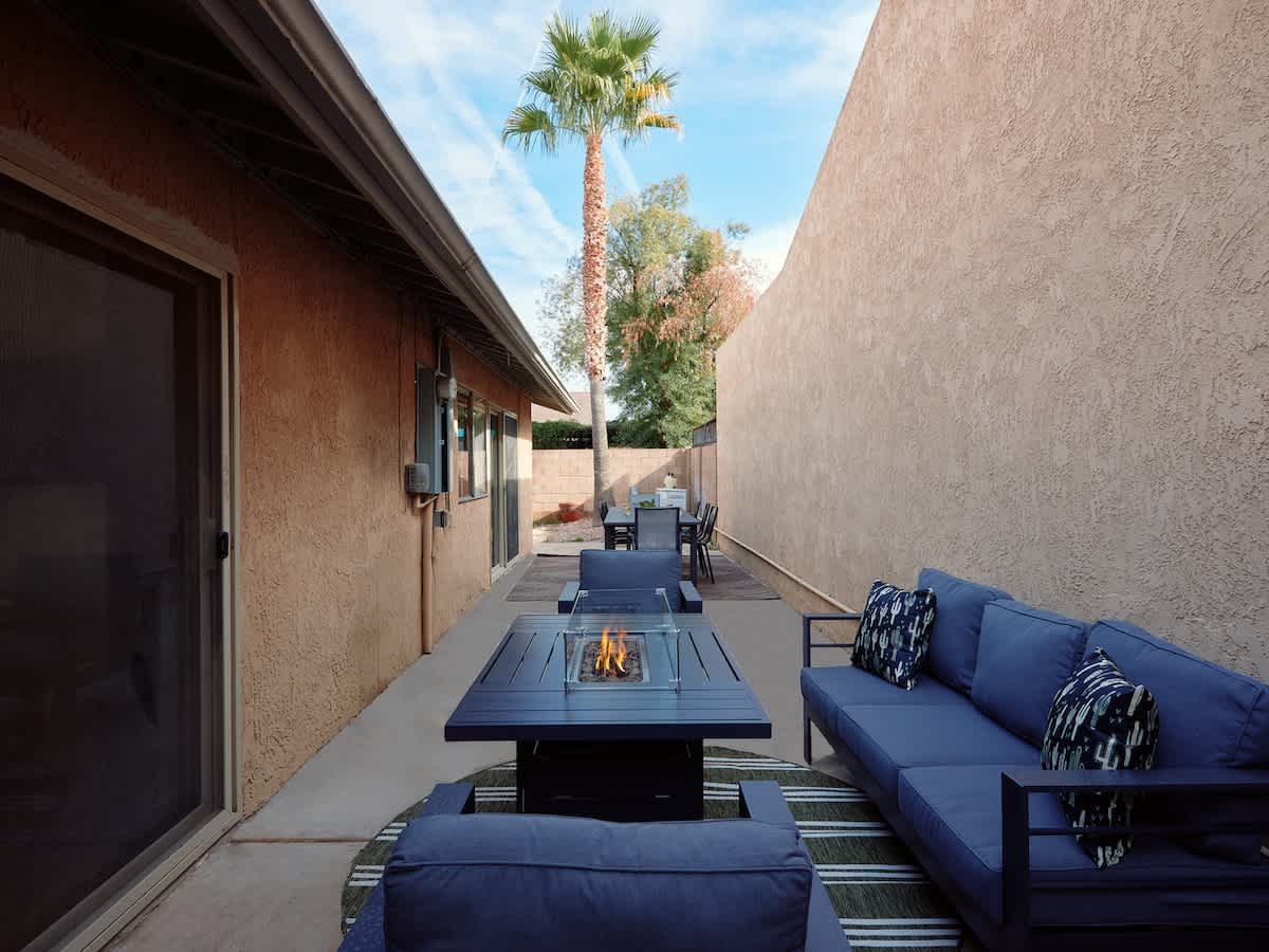 Private backyard with a sparkling pool, sun loungers, outdoor dining area with seating for 8 guests and a lounge area surrounding a fire pit.