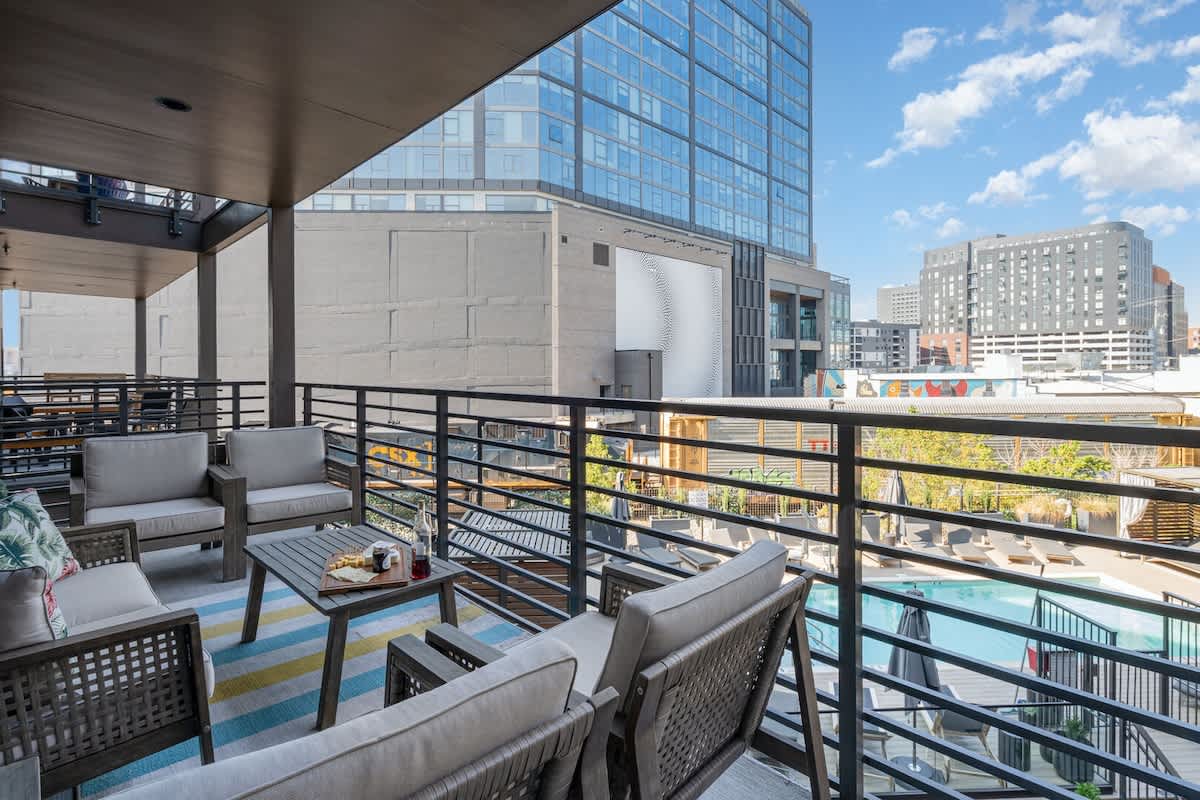 Spacious fourth-story balcony with ample seating and stunning views of the pool and city—perfect for lounging day or night.