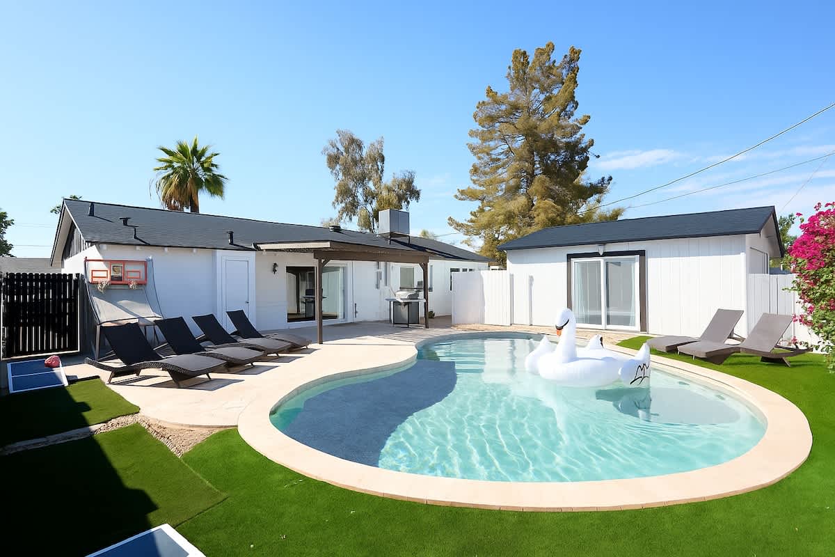 Backyard paradise with a sparkling pool, loungers, cornhole, and a basketball arcade game for non-stop fun.