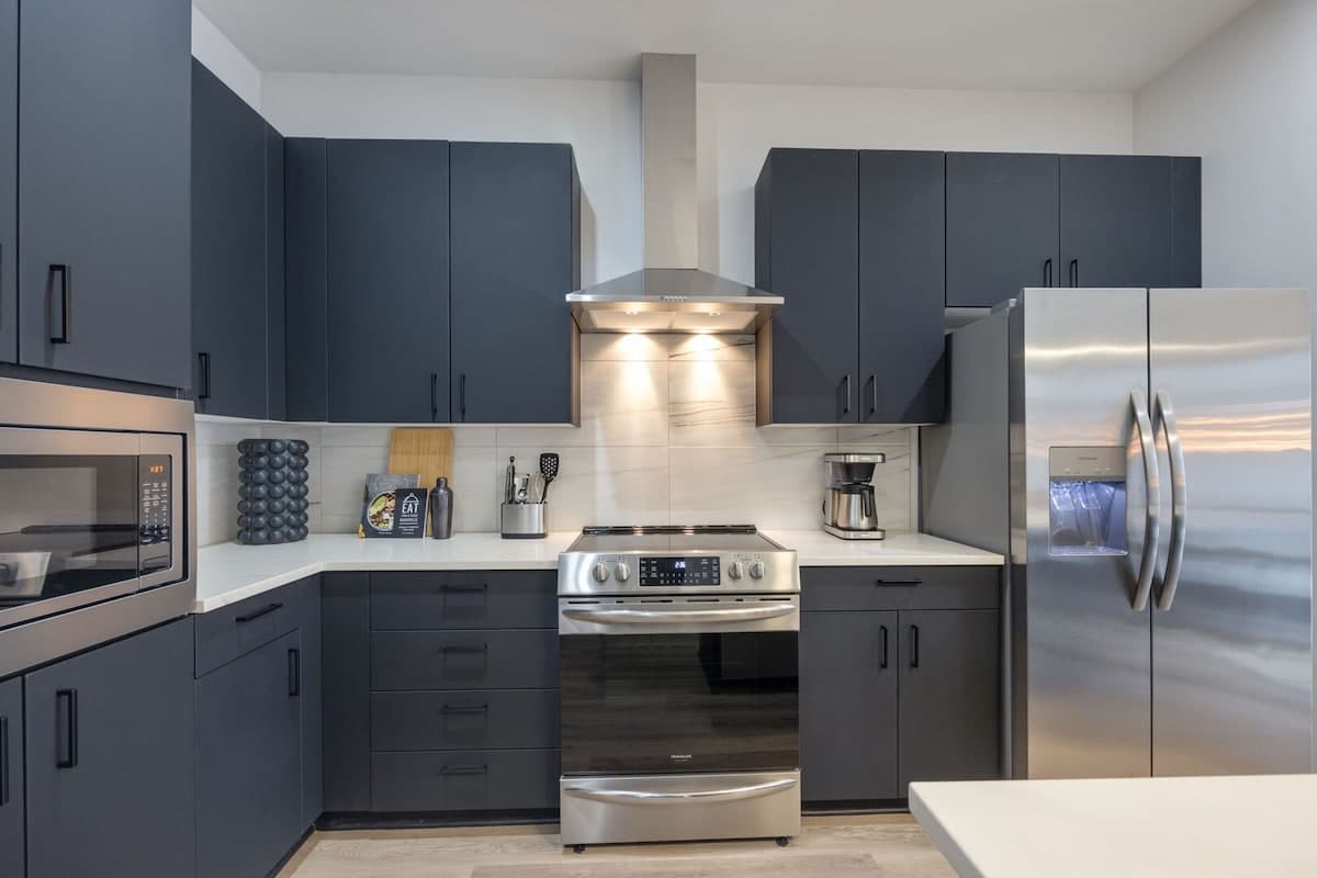 Fully equipped kitchen with stainless steel appliances, basic cooking essentials, toaster, coffee machine, and kitchen island seating.