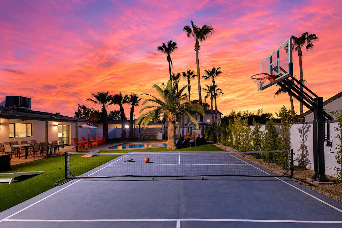 Resort-style backyard featuring a private pool, poolside loungers, a multi-sport court for basketball, pickleball, and tennis, turf with cornhole, a pergola with a built-in BBQ and bar seating, and a
