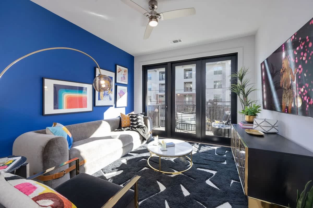 Unit 1: Bright open living space featuring a smart flat-screen TV, designer furnishings throughout, and access to a private patio.