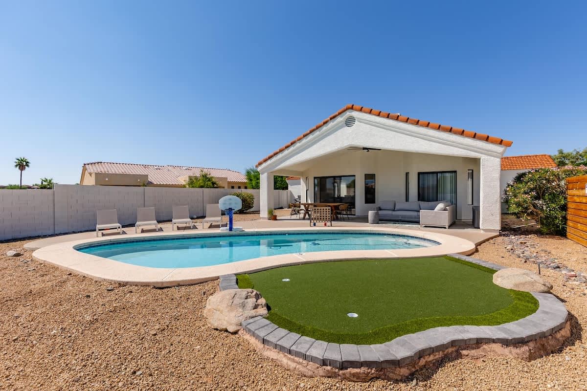 Sparkling heated pool, putting green, fire pit, sun loungers, BBQ, cornhole, and outdoor patio furniture, plus dining area.