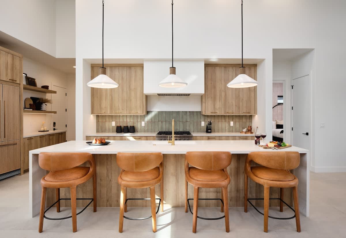 Fully equipped kitchen boasting high-end stainless steel appliances and a large island offering bar seating overlooking the formal dining area.