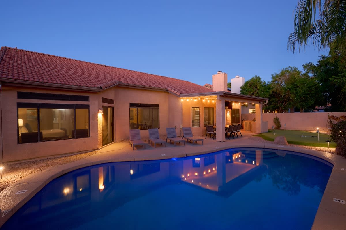 Private backyard paradise featuring a pool, sun loungers, mini golf, a covered patio with an outdoor dining area, and a BBQ with bar seating.