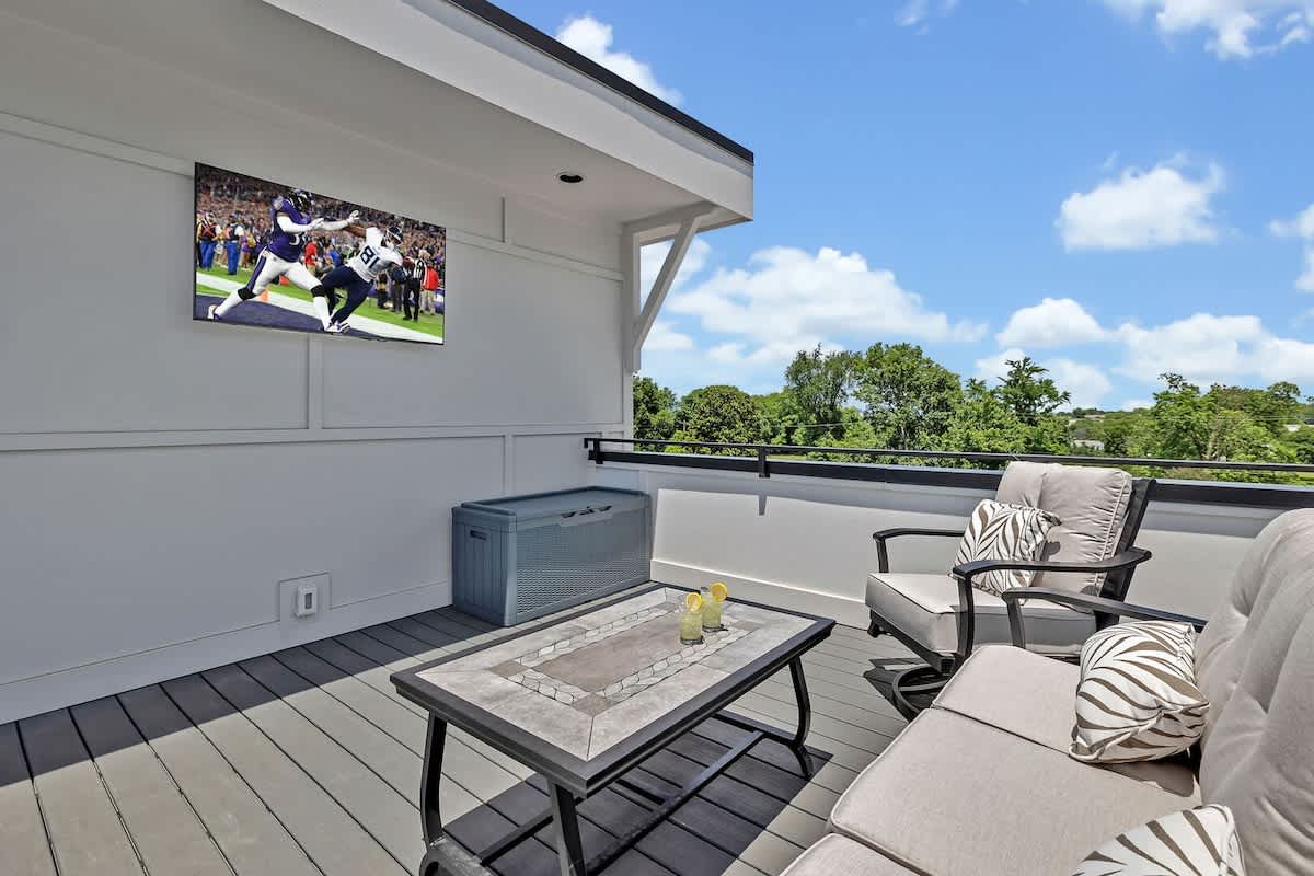 Unit 1 - 4th Floor: Private rooftop patio featuring outdoor furnishings for lounging and a Smart TV for entertainment surrounded by beautiful neighborhood views.