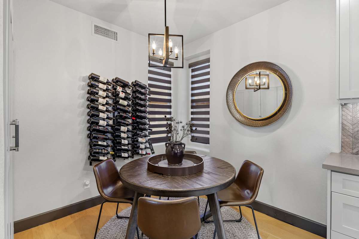 Enjoy intimate meals in this stylish dining nook, featuring a round wood table that seats 4, statement lighting, and chic leather chairs.