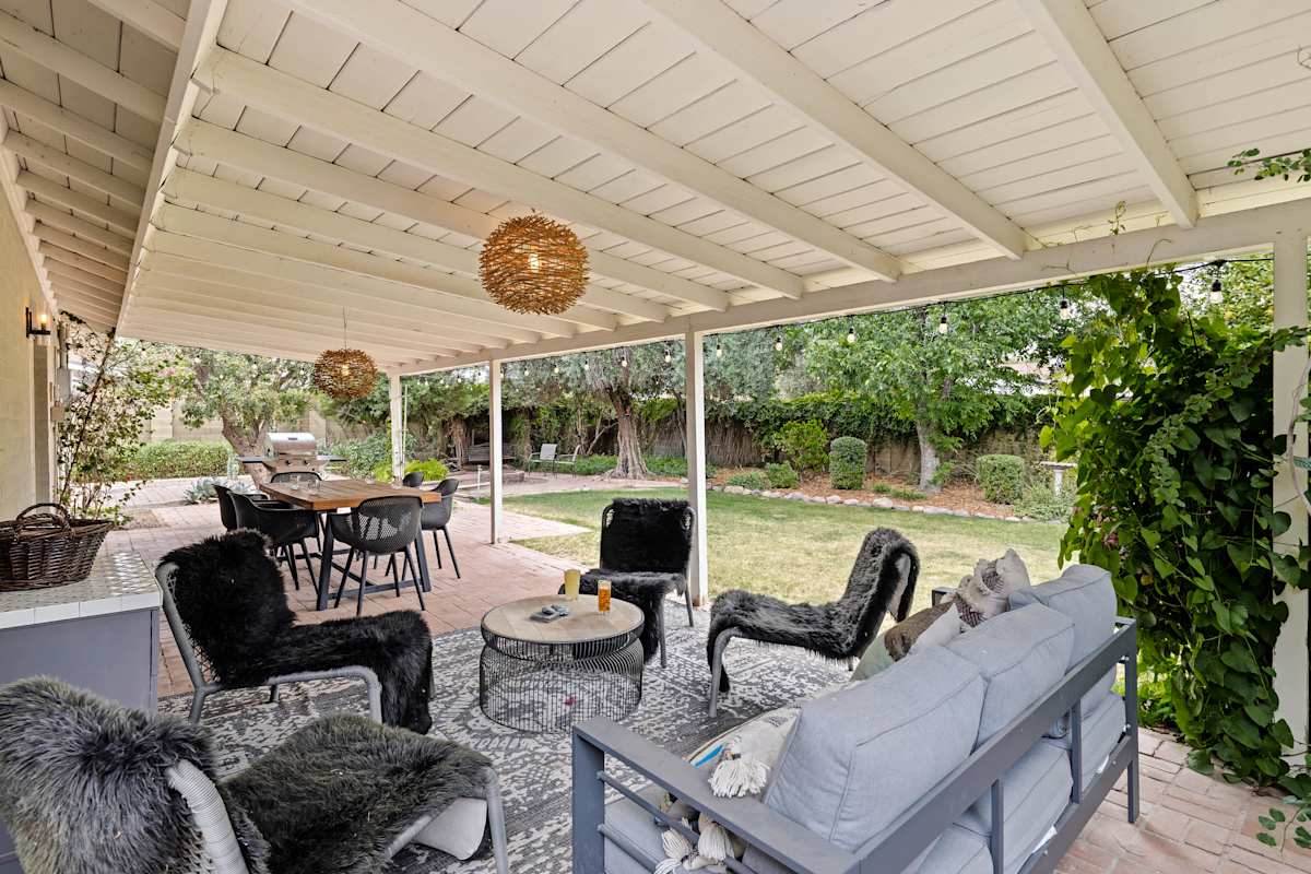 Private backyard featuring a covered patio with an outdoor lounge area and dining area, BBQ grill, and outdoor seating.
