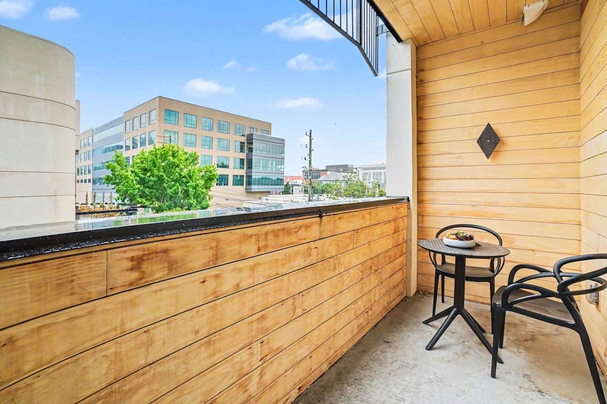 Unit 2: The private balcony offers a breezy urban escape with warm wood surrounds, seating for two and open skyline views of the city.