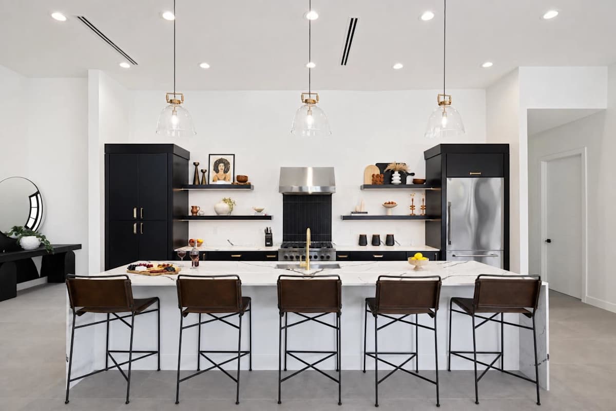 Large open-concept kitchen with brand new stainless steel appliances, quartz counter tops, large island with breakfast bar seating, and designer decor.