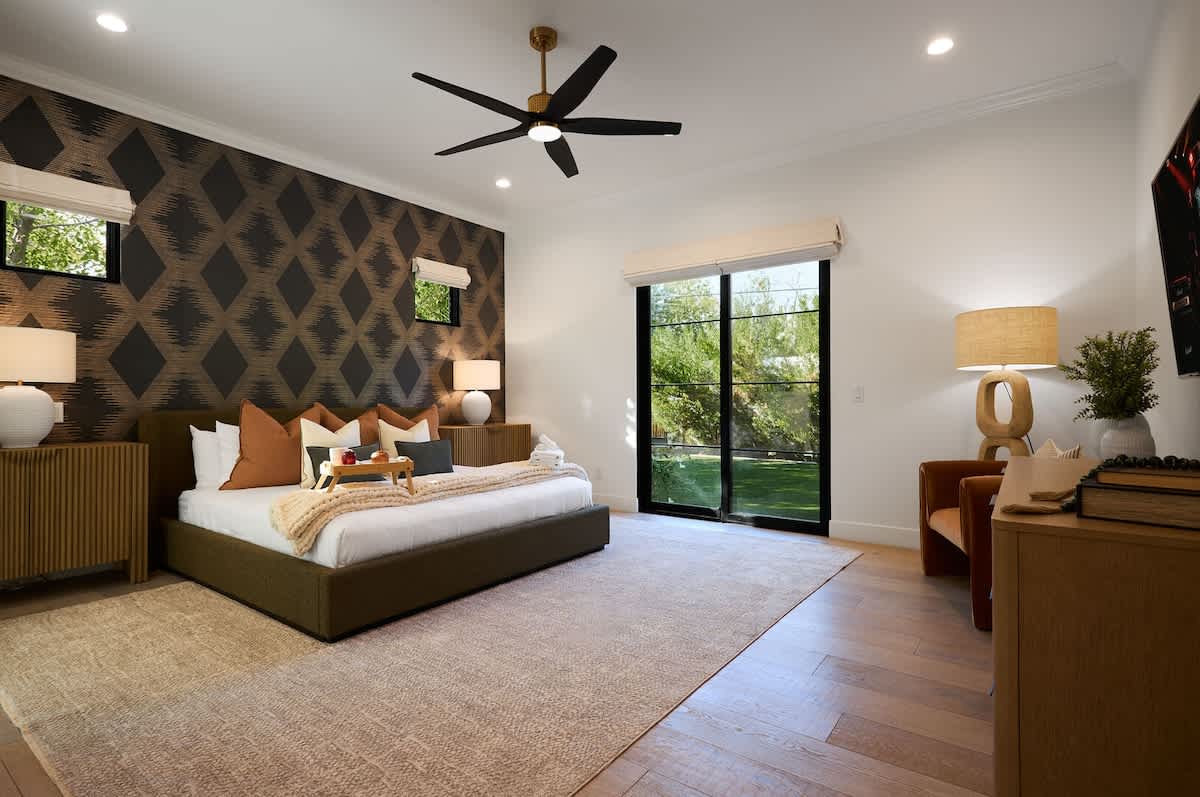 Primary Bedroom featuring a King bed, smart TV, designer furnishings, en-suite bathroom, and backyard access.