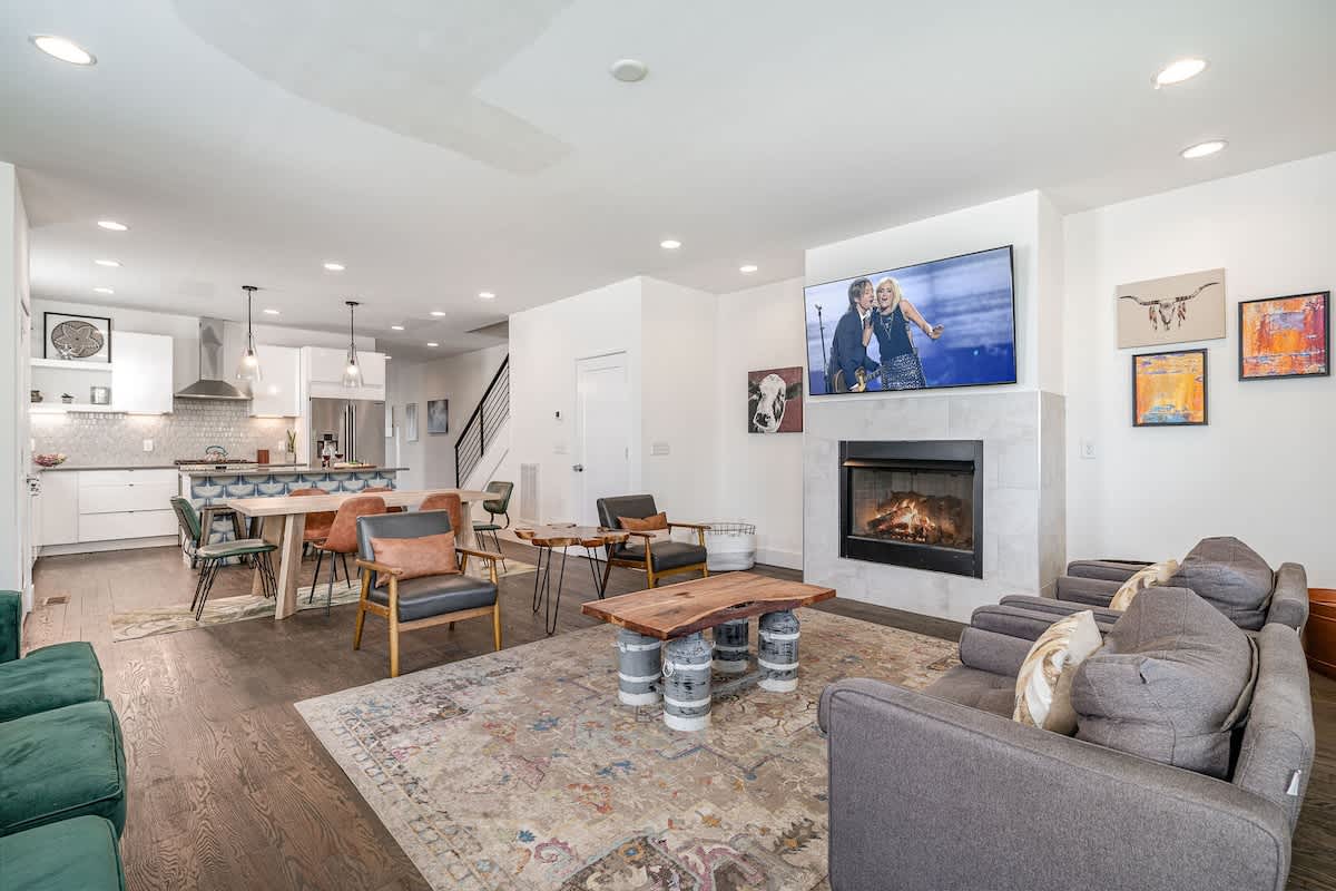 Welcoming living area with a vibrant green accent wall, large Smart TV, fireplace, and plush seating arranged to take in the serene outside views. (1st Floor)
