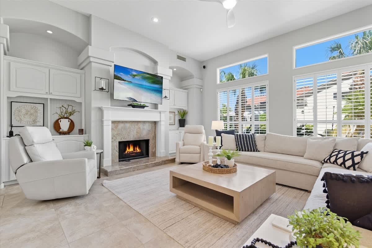 The primary living area features a sectional, cozy armchairs, a fireplace, and a smart TV, with large windows that fill the room with natural light.