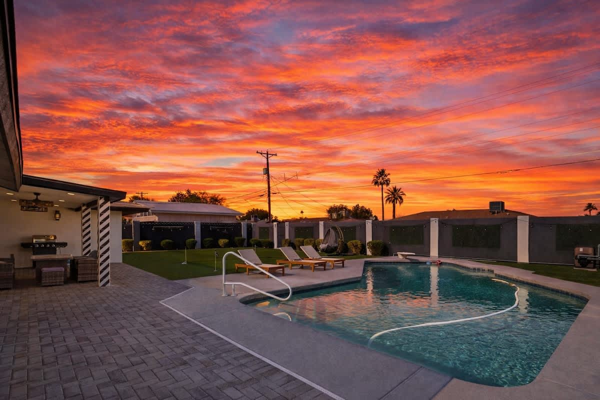 Private backyard featuring a sparkling pool, sun loungers, mini golf, and a covered patio with outdoor seating, and a BBQ grill.