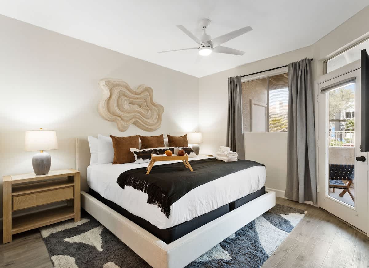 Spacious primary bedroom with a king bed, direct patio access, smart TV, a walk-in closet, and a private en-suite bathroom for ultimate comfort and convenience.