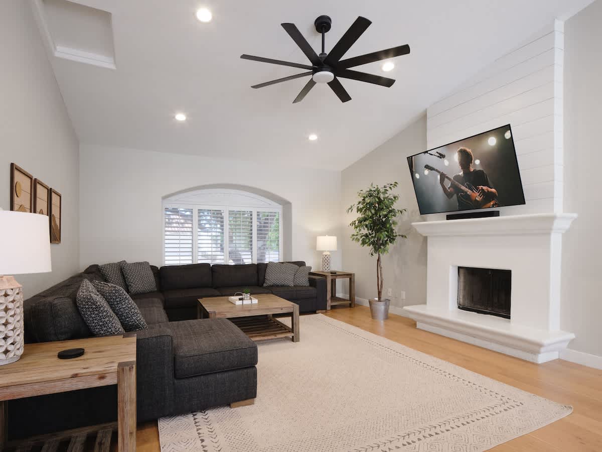 Bright open floor primary living area, modern furnishings, smart TV, and easy access to the dining and kitchen area. Fireplace for display only. (1st Floor)