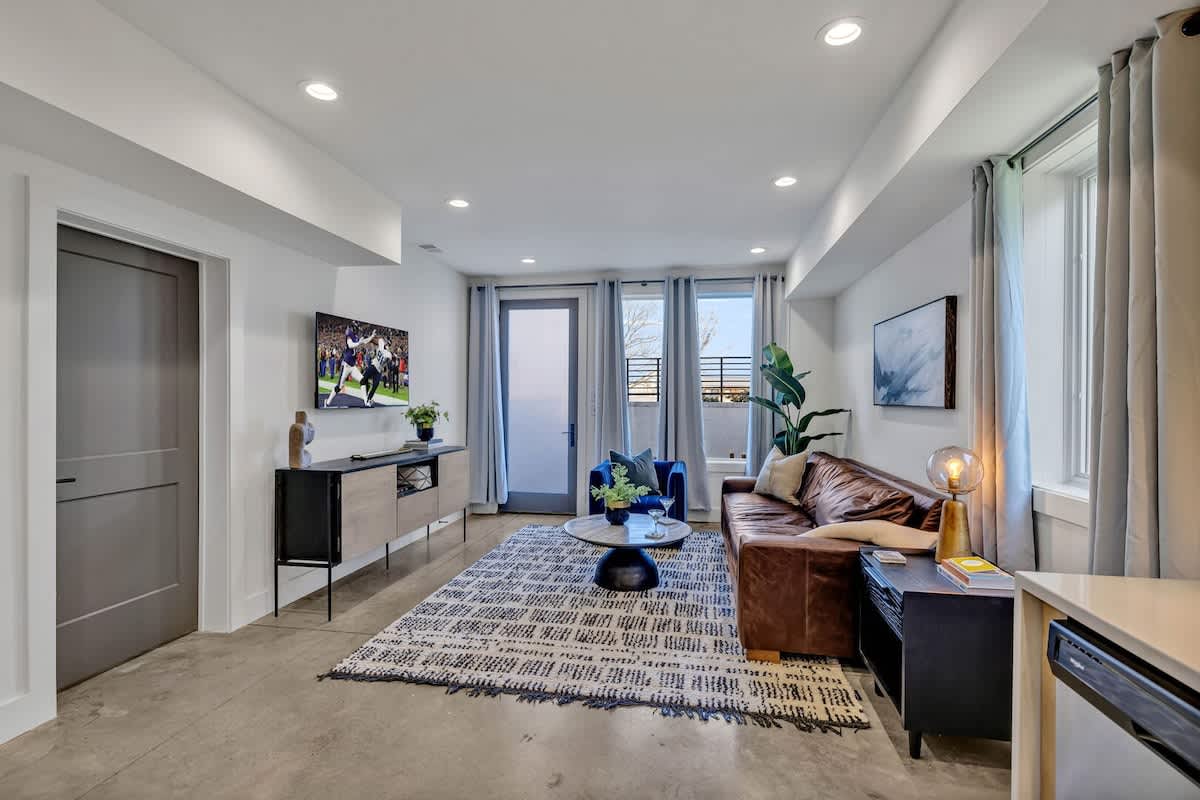 Open-concept living space featuring a comfortable sectional with a Smart TV for entertainment and a fully equipped kitchen stocked with all culinary essentials and stainless steel appliances.