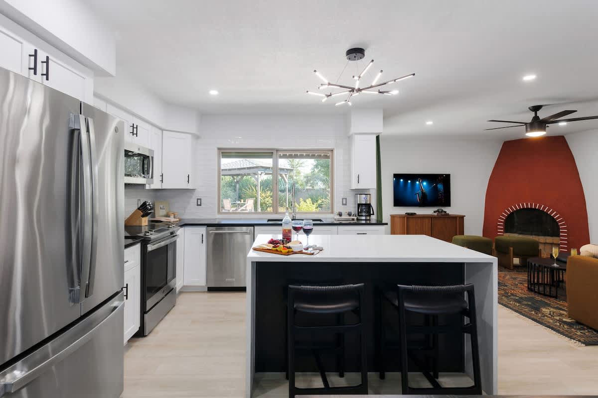 Fully equipped kitchen with stainless steel appliances, a sleek kitchen island with a breakfast bar for casual seating for 2, plus a large dining table for 4.