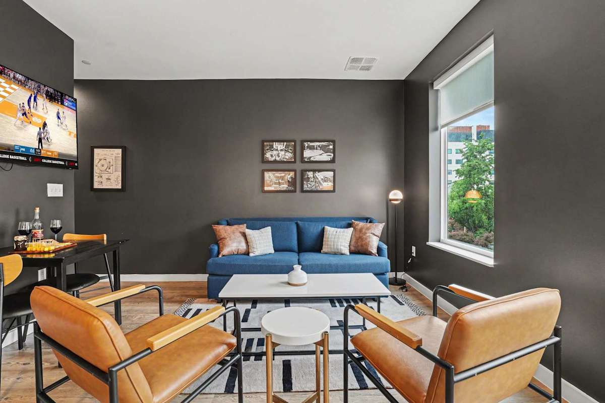 Bright open floor living space featuring a smart flat-screen TV and designer furnishings. Connects to the dining area and kitchen. Sofa is also a sleeper sofa. 