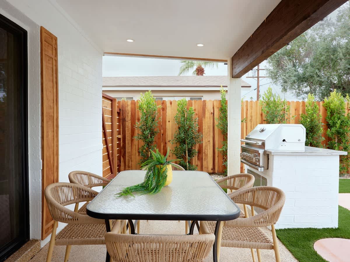 Private backyard featuring a sparkling pool and spa, sun loungers, and a covered patio with outdoor seating, dining area, bathroom, and a BBQ grill.