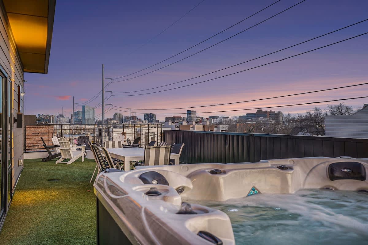 Expansive patio with stunning views of Downtown Nashville, plenty of outdoor seating, a hot tub, fire pit, outdoor dining area, sun loungers, and outdoor games.