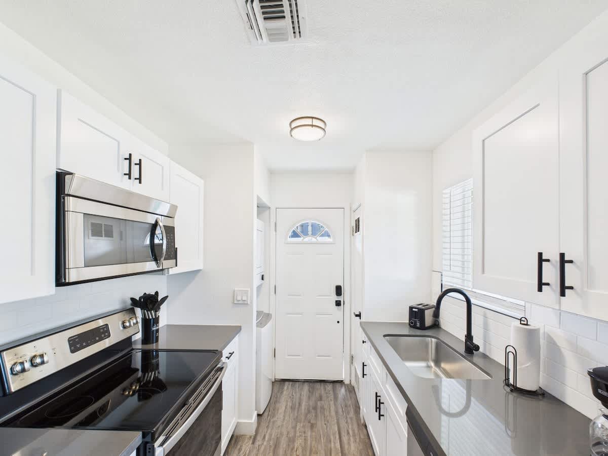 Fully equipped kitchen stocked with basic cooking essentials, stainless steel appliances, access to the shared backyard, and a washer and dryer.