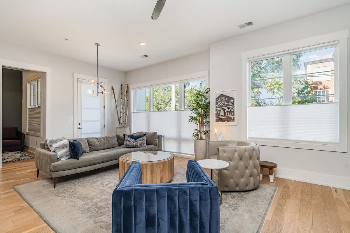 Bright open floor living space featuring designer furnishings and a smart flat-screen TV, and access to a private balcony.