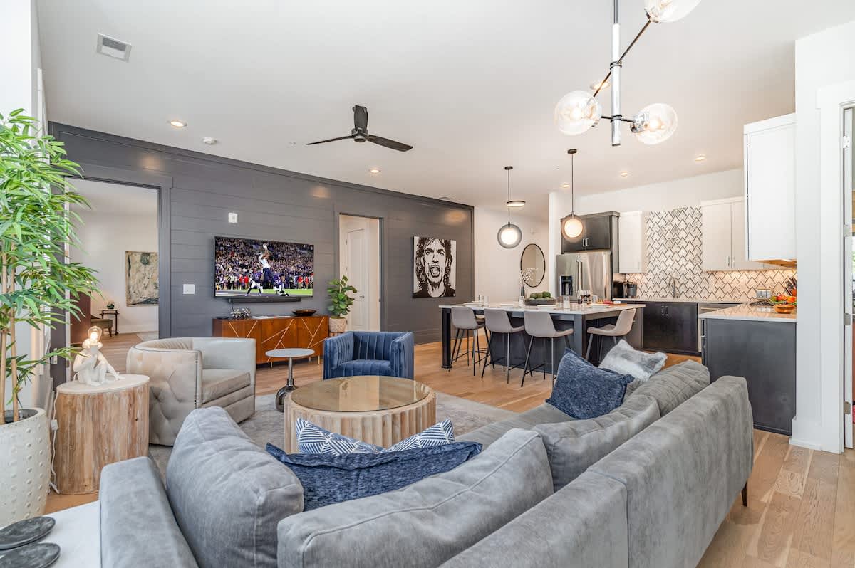 Bright open floor living space featuring designer furnishings and a smart flat-screen TV, and access to a private balcony.