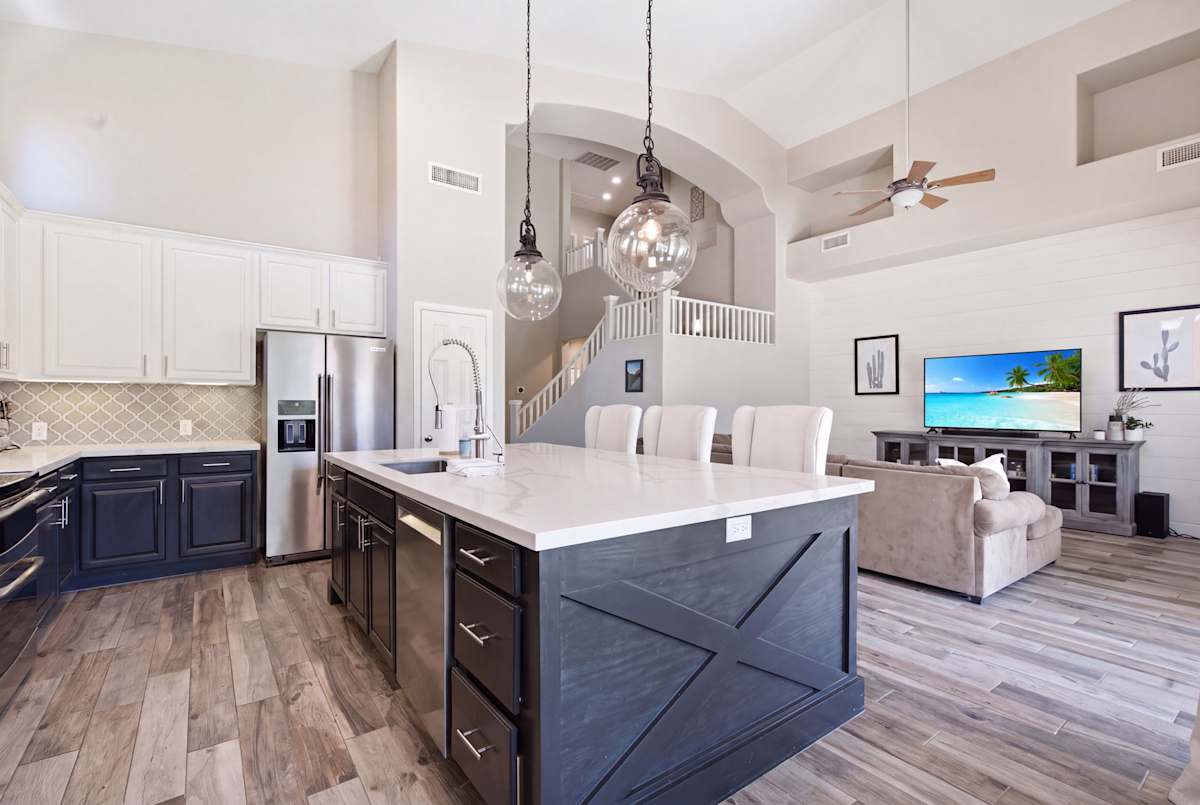 The kitchen's two-toned cabinetry and quartz counters wrap around a spacious island with seating for four, all finished with stainless steel appliances and a designer arabesque tile backsplash.