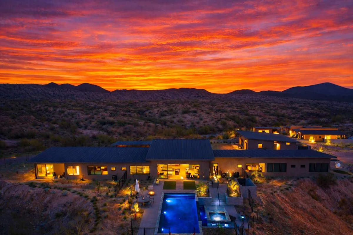 Stunning private oasis featuring a sparkling heated infinity pool and spa with sun loungers, a patio with a BBQ grill, multiple lounge areas, and fire pits surrounded by unparalleled desert views.