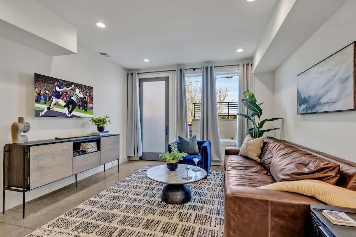 Lower Unit: Open-concept living space featuring a comfortable sectional with a Smart TV for entertainment and a fully equipped kitchen stocked with all culinary essentials and stainless steel applianc