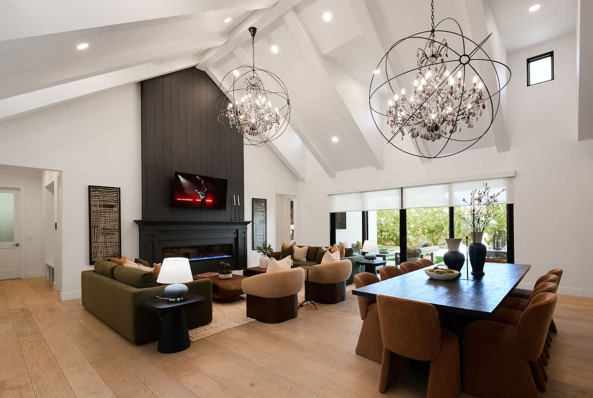 Open living area featuring designer furnishings, a Smart TV, fireplace, dining area, and access to the backyard.