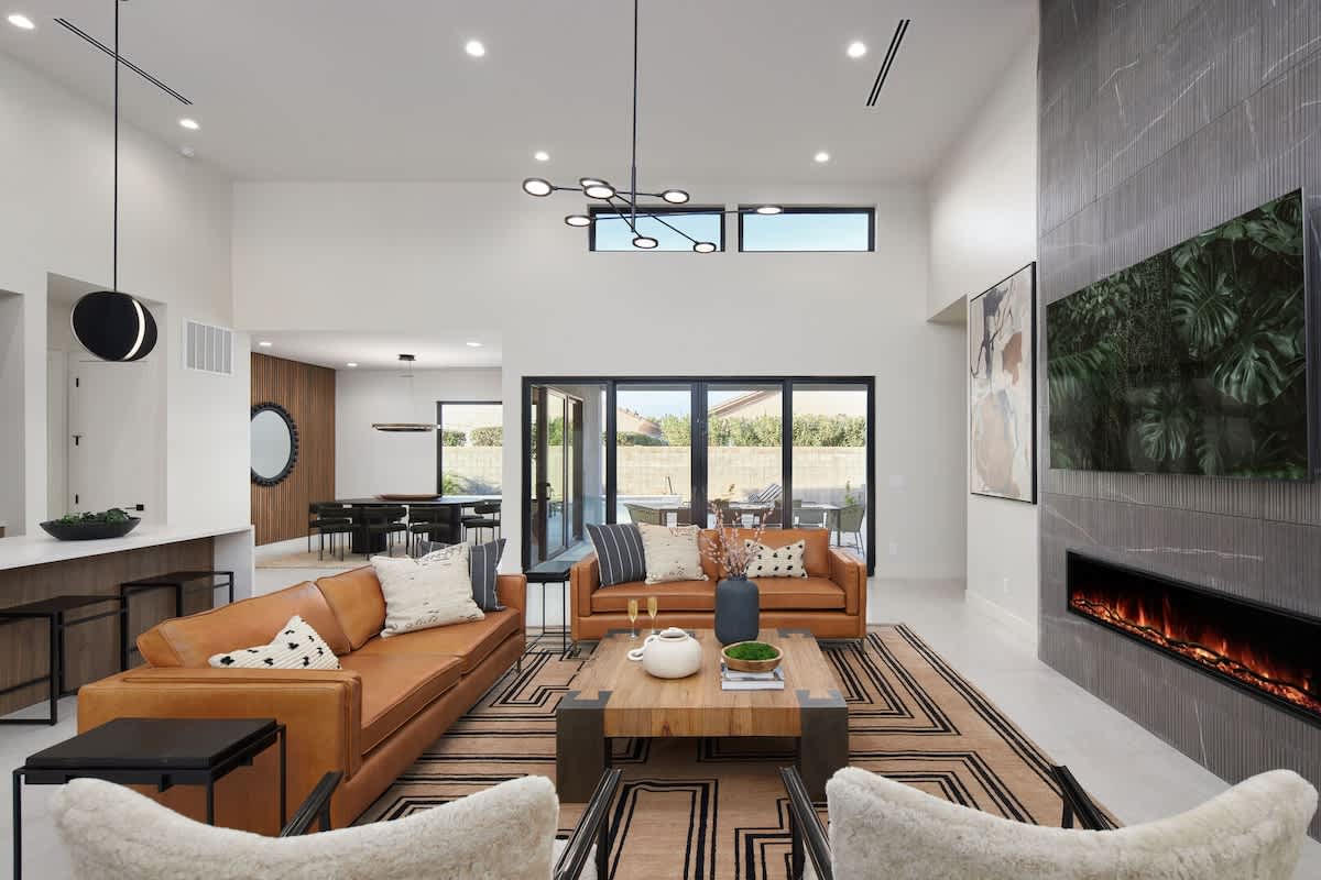Grand living space featuring sky-high ceilings, an electric fireplace and a Smart TV complete with contemporary designer furnishings.