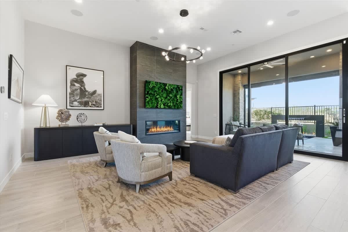 Living room offers a warm and modern atmosphere with a sleek fireplace, cozy seating, and expansive glass doors that open to the patio.