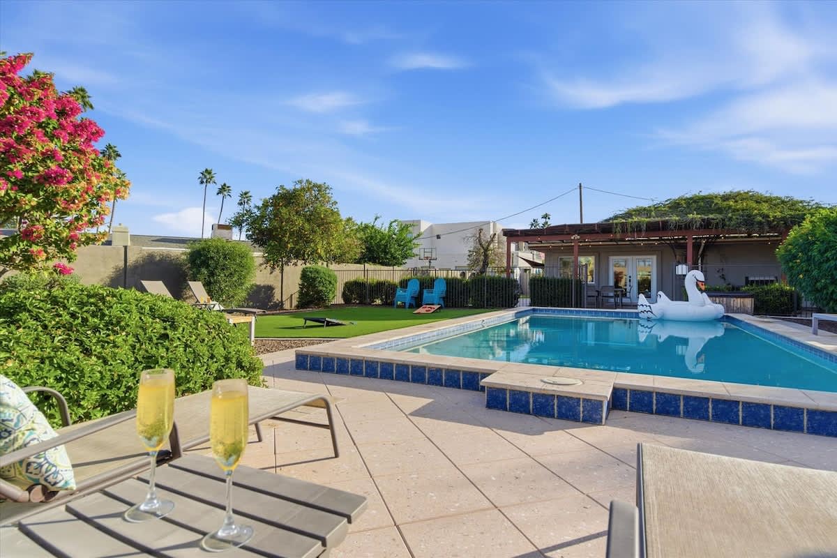 Private backyard with a sparkling pool, sun loungers, outdoor games, and a covered patio with an outdoor dining area and a BBQ grill.