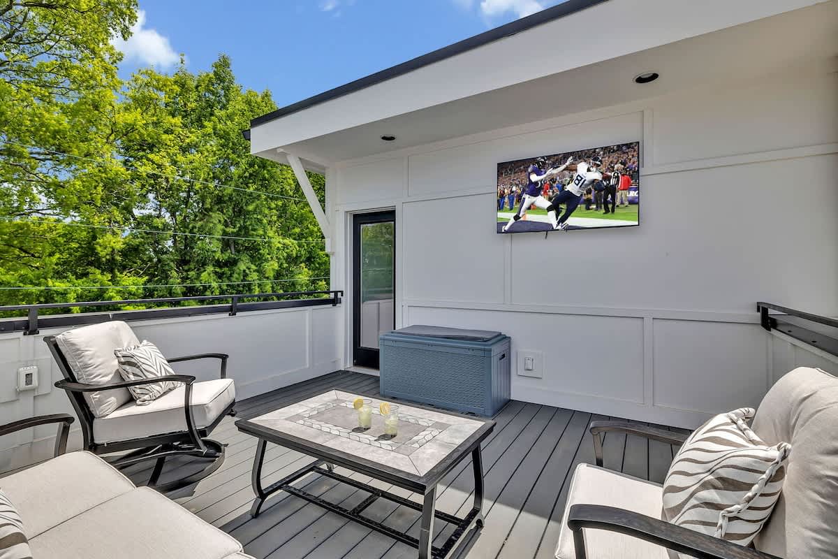 Unit 1 - 4th Floor: Private rooftop patio featuring outdoor furnishings for lounging and a Smart TV for entertainment surrounded by beautiful neighborhood views.