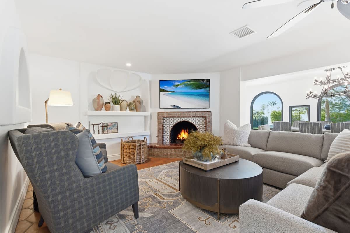 Bright open floor living area, modern furnishings, smart TV, gas fireplace, and easy access to the dining and kitchen area.