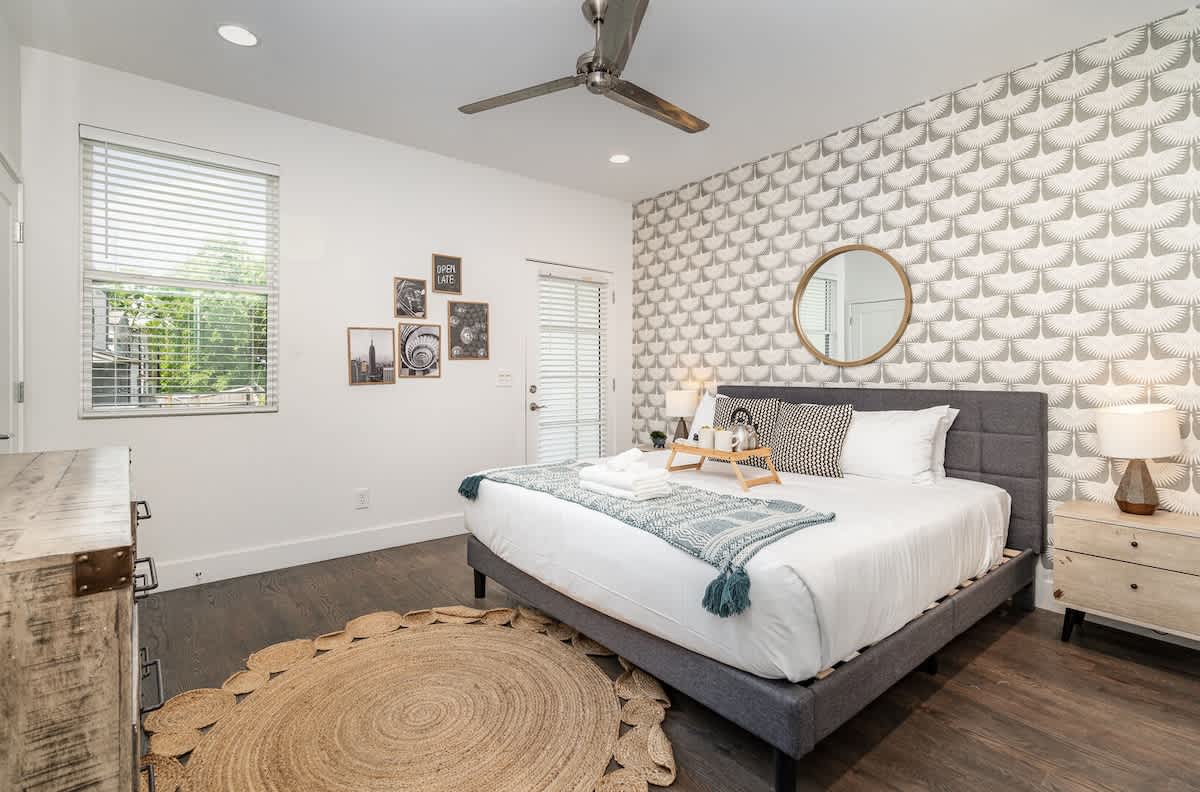Unit 2: Primary bedroom offers a king bed, accent wall, Smart TV, private balcony, and en-suite bath.