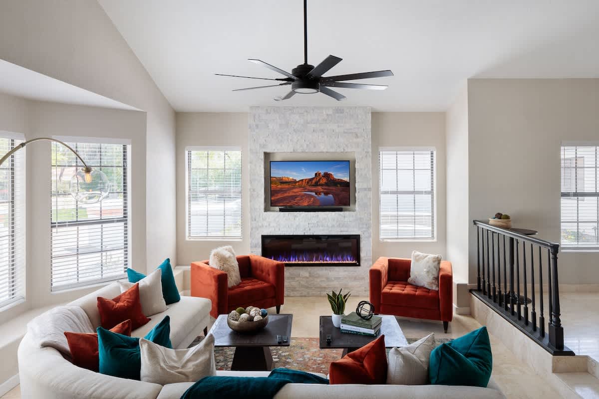 Bright, open-floor formal living space features a smart flat-screen TV, designer furnishings, and an electric fireplace. (1st Floor)