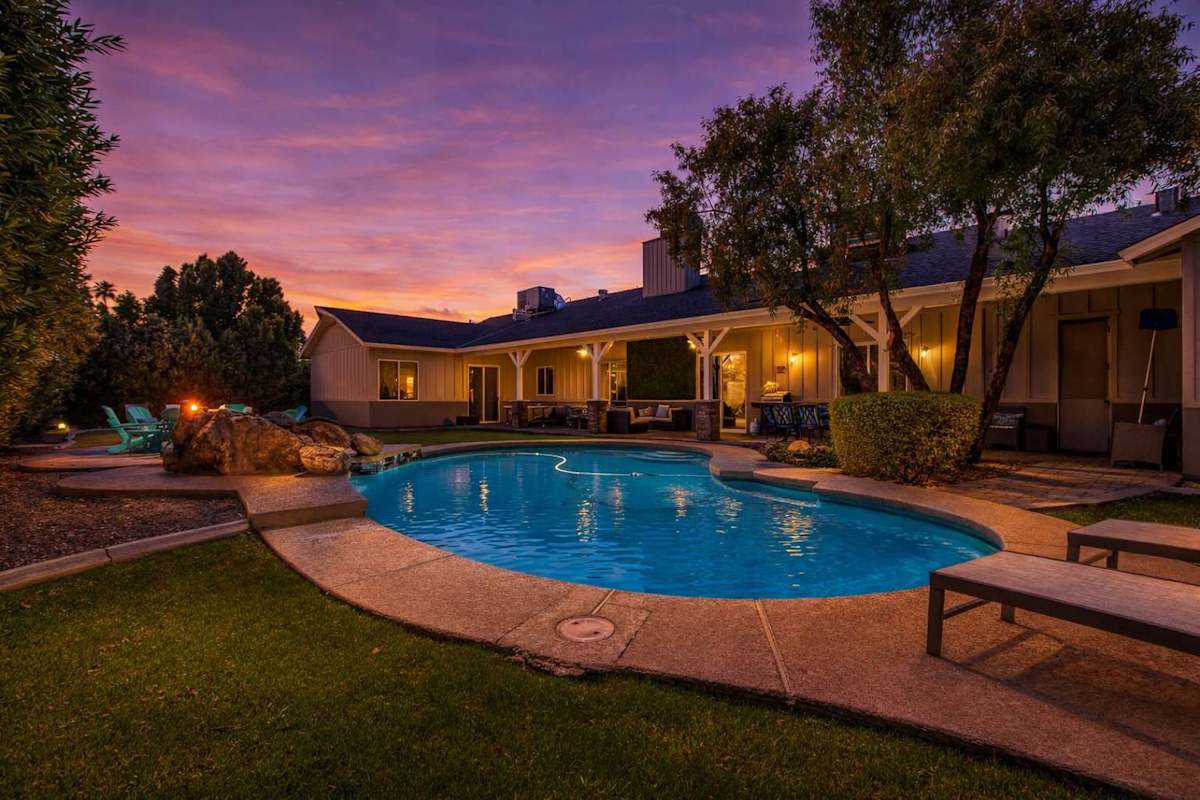 Backyard with covered patio, multiple seating areas, ping pong table, yard games, BBQ grill, fire pit, sun loungers, and sparkling pool.