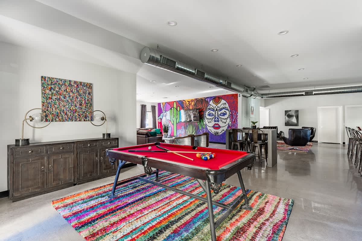 Open-floor living space featuring a Smart TV, designer furnishings, a beautiful mural on the wall, dining table, and a pool table.