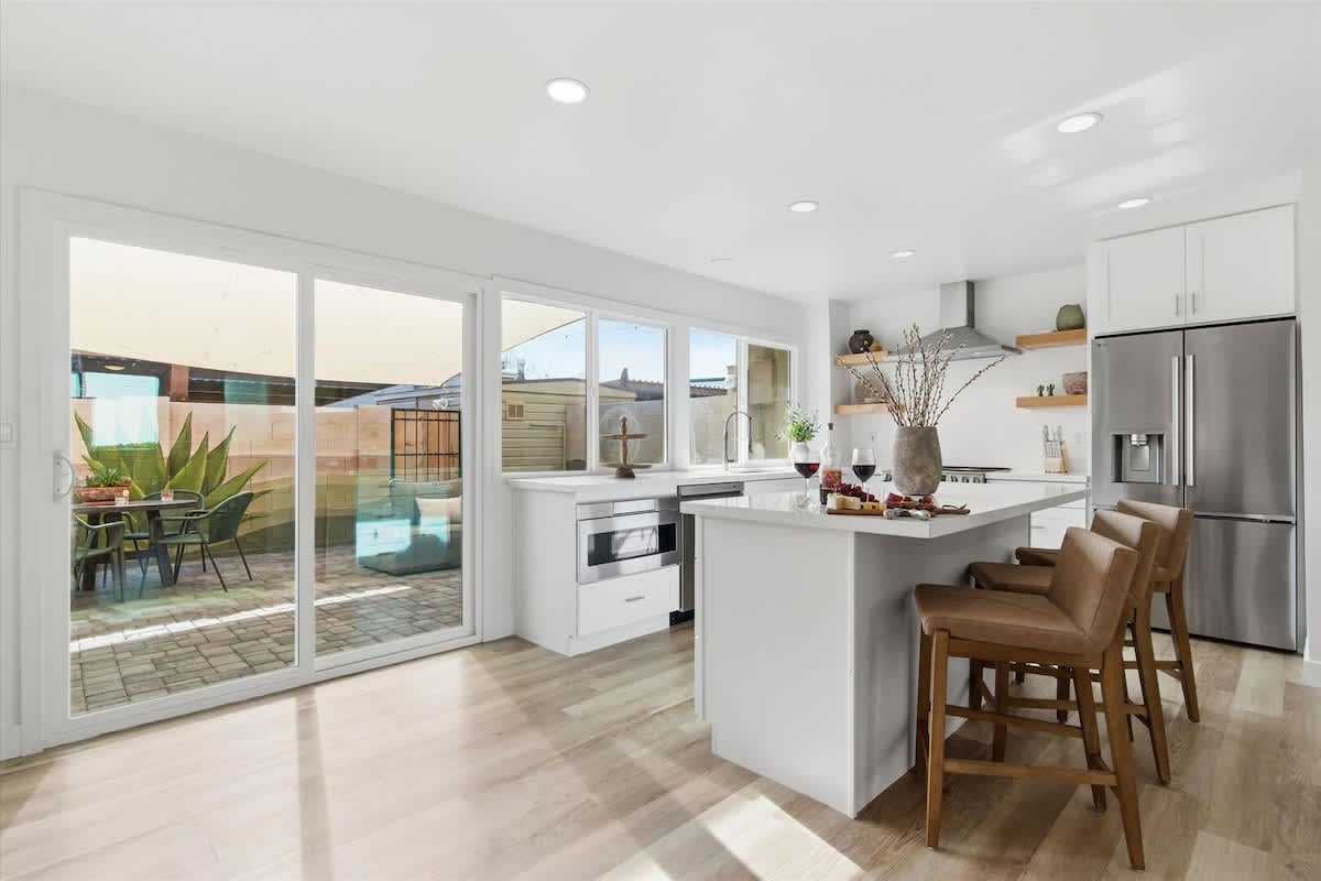 Fully equipped kitchen with stainless steel appliances, bar seating for three, and a coffee bar with a drip coffee maker and a mini fridge.