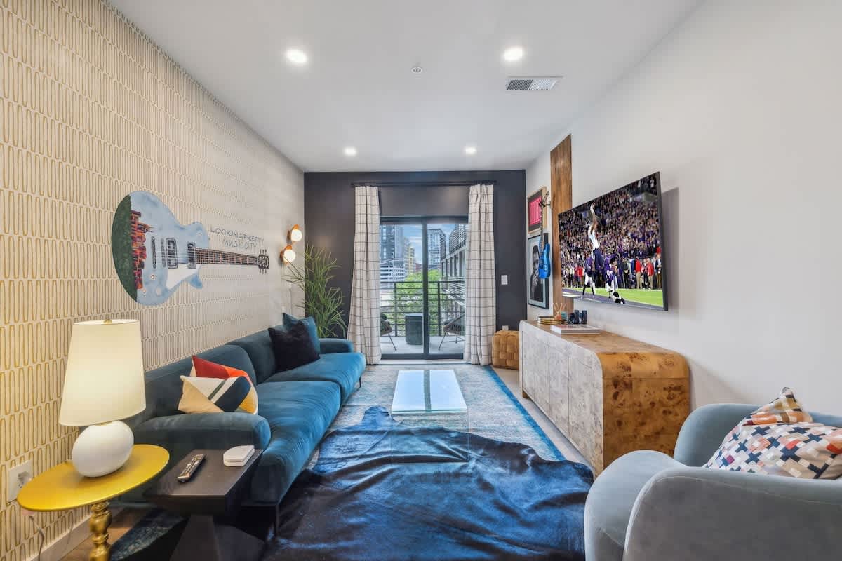 Warm and stylish living room featuring a large Smart TV, elegant furnishings, and a spacious balcony.