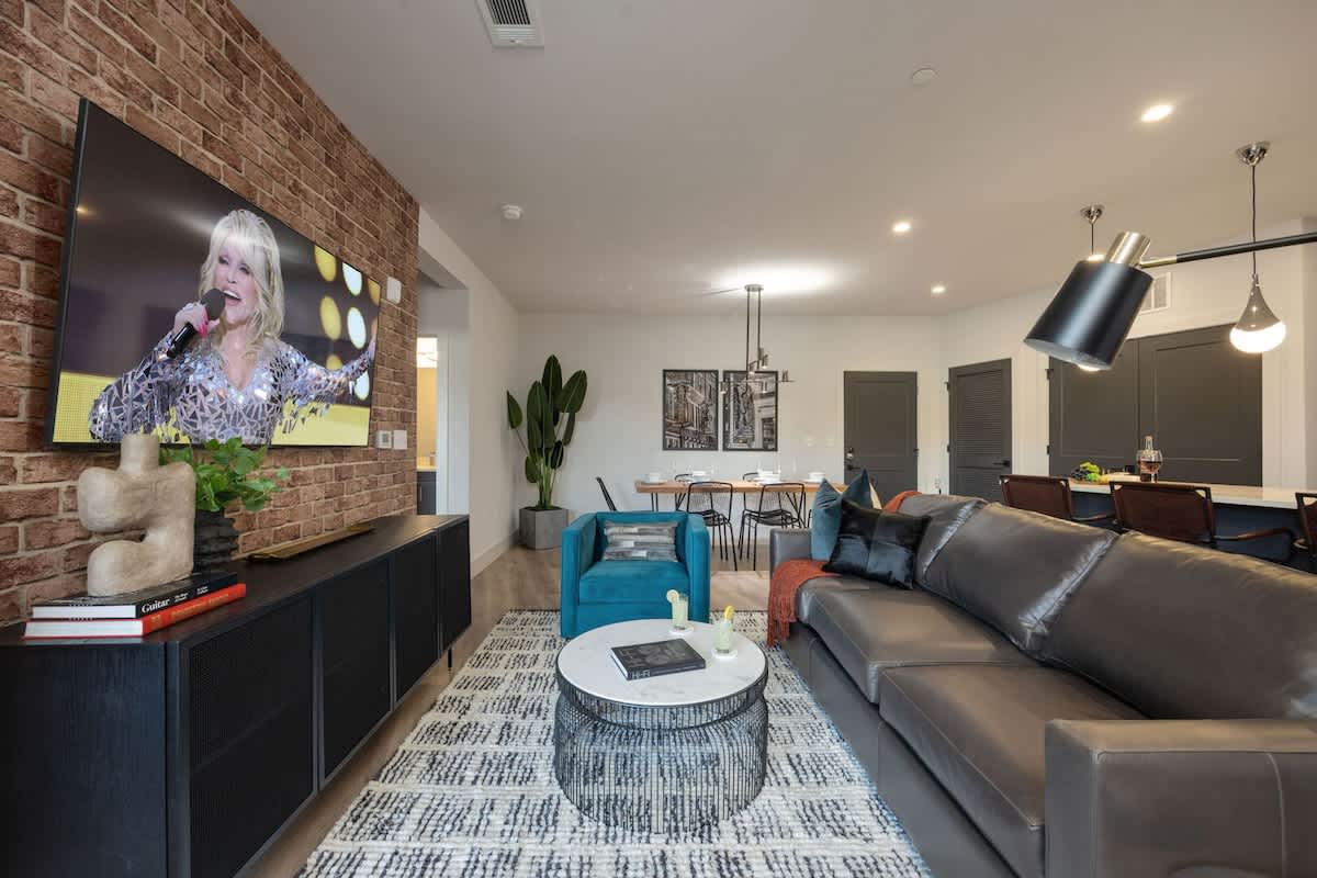 Bright open-concept living space featuring comfortable seating, smart TV, designer furnishings, and access to the private patio.