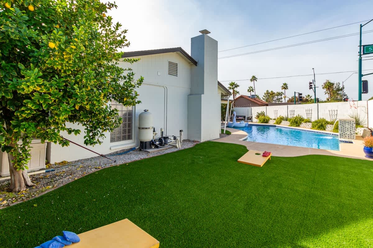 Private yard with sparkling pool, sun loungers, cornhole, and outdoor covered patio with BBQ grill.