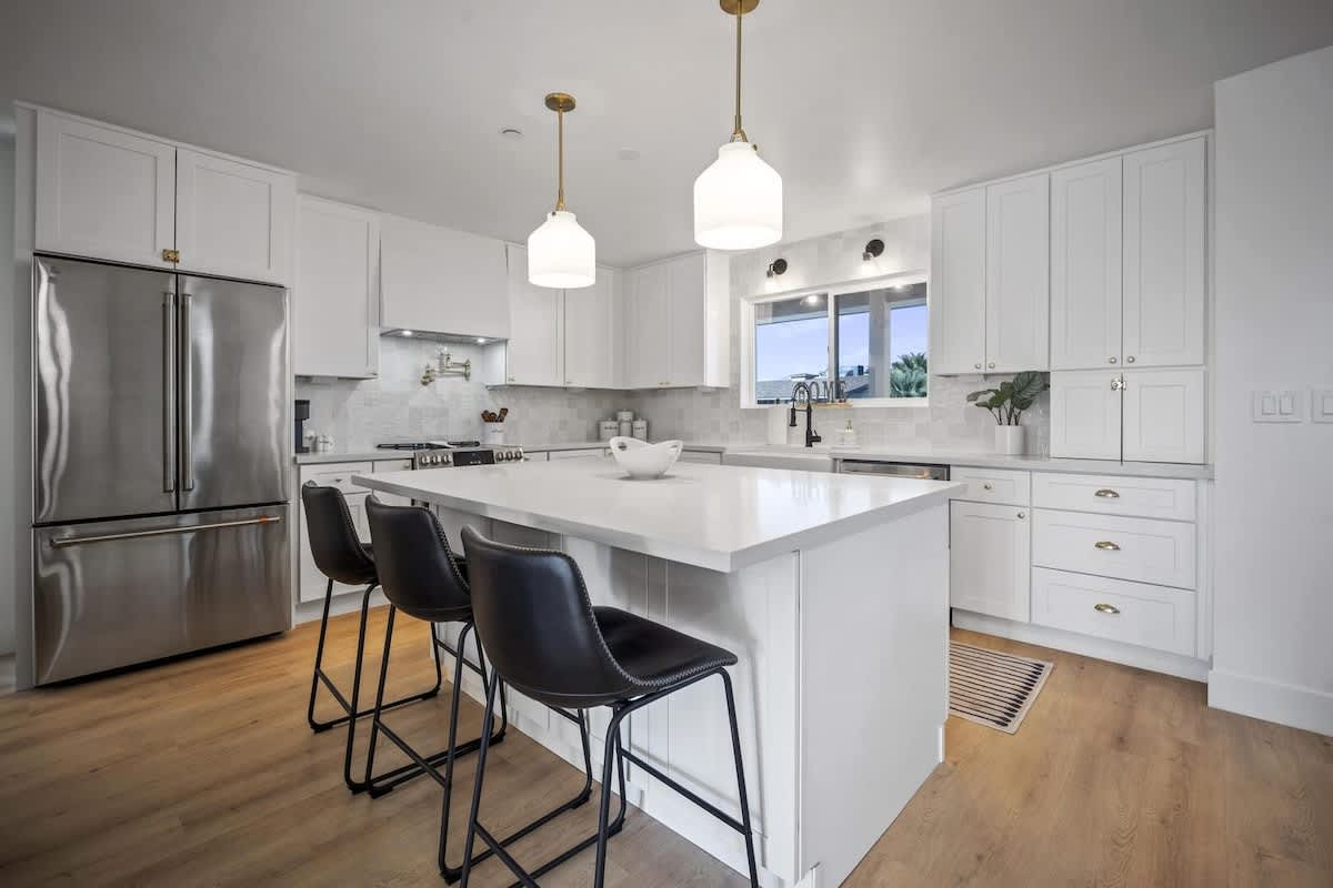 Bright, modern kitchen with a spacious island, sleek white cabinetry and stainless steel appliances.
