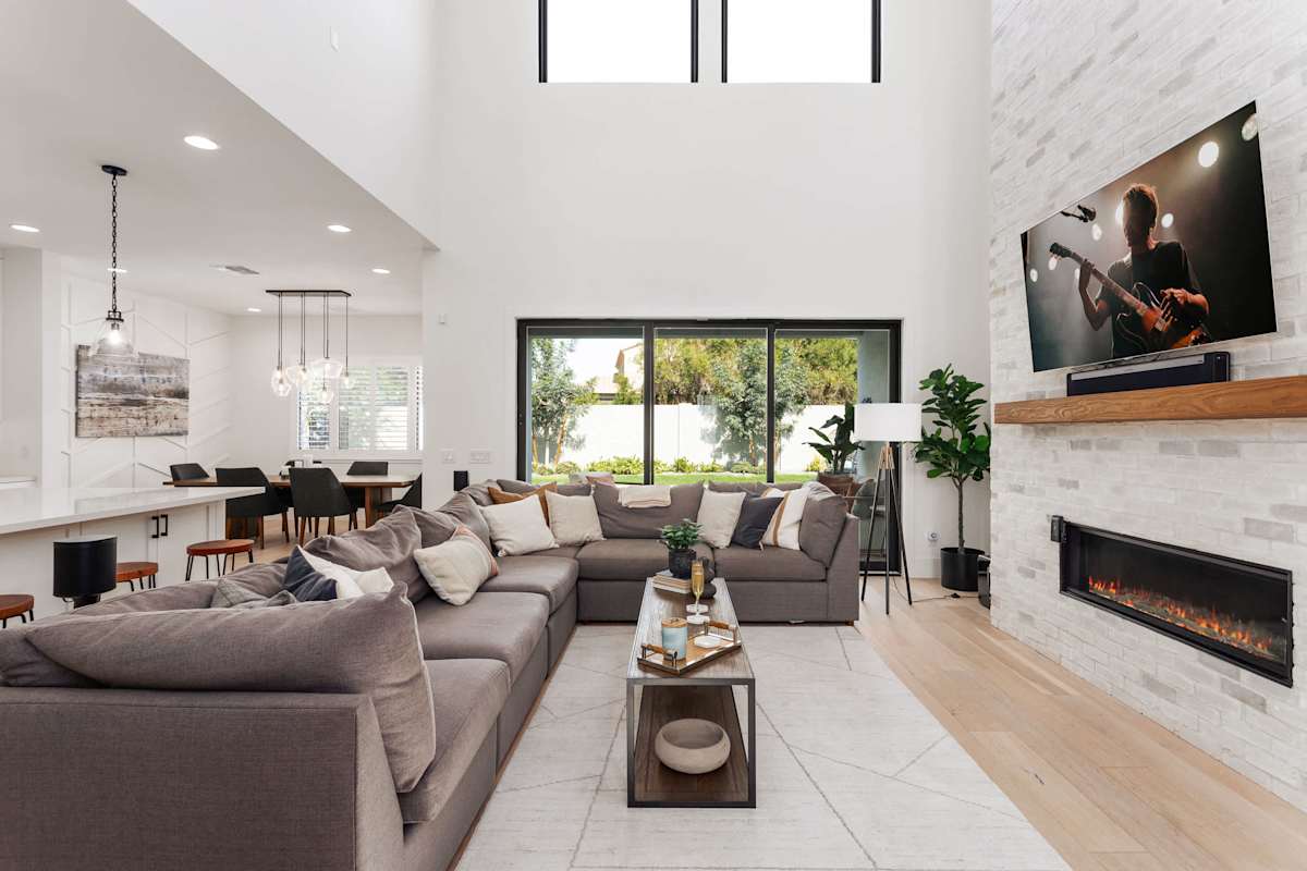 Main living area featuring designer furnishings, Smart TV, fireplace, and access to the backyard.