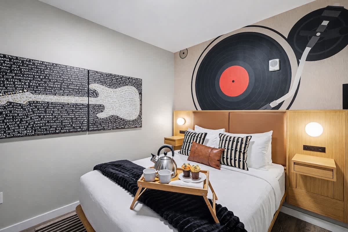 The primary bedroom features a plush Queen-sized bed with a wall-mounted smart TV and includes closet space to store your belongings.